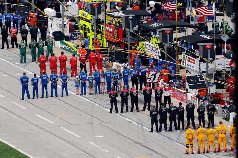 Pit crew members bow their heads for a prayer during the NASCAR Sprint Cup Duck Commander...