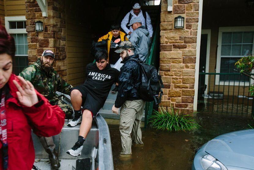 Clyde Morales of St. Gabriel, La., left, part of the volunteer Cajun Navy, helps evacuees...