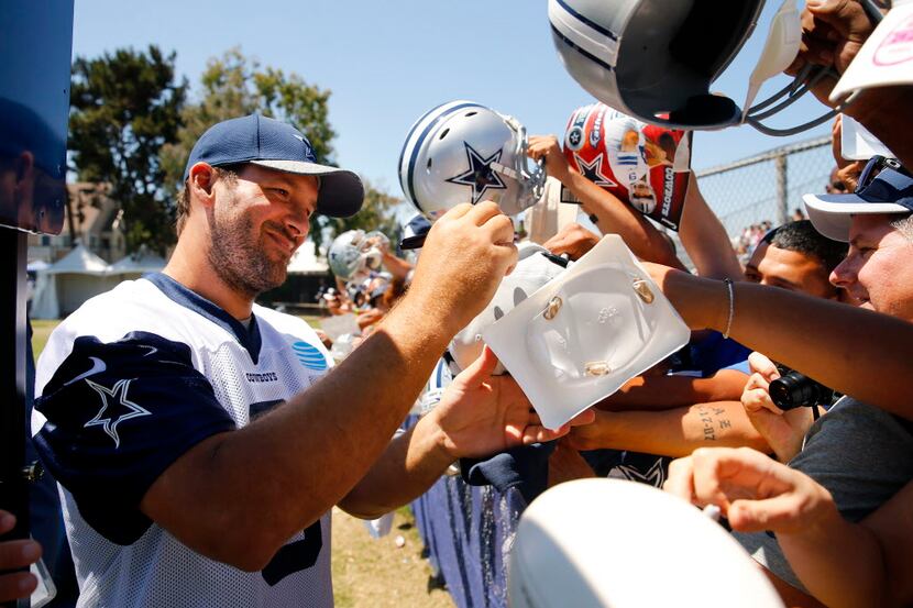 Dallas Cowboys quarterback Tony Romo (left) signs autographs for fans following the final...