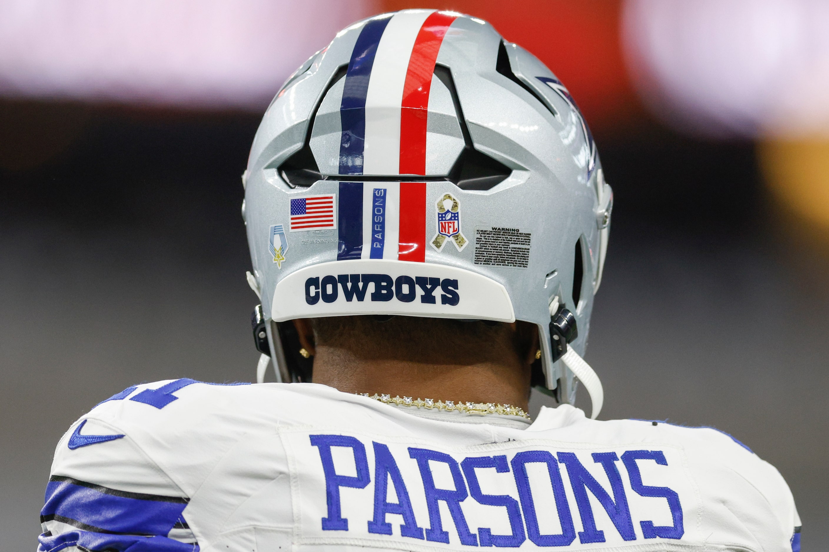 Dallas Cowboys linebacker Micah Parsons wears a helmet featuring a red stripe and ribbon in...