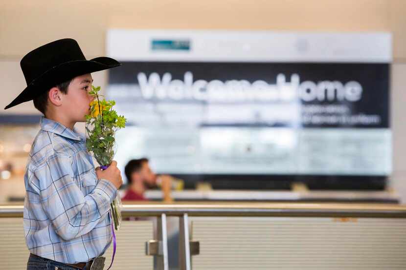 
Ben Mackey, 8, holds flowers as he waits for his aunt Danielle Banks to arrive at DFW...