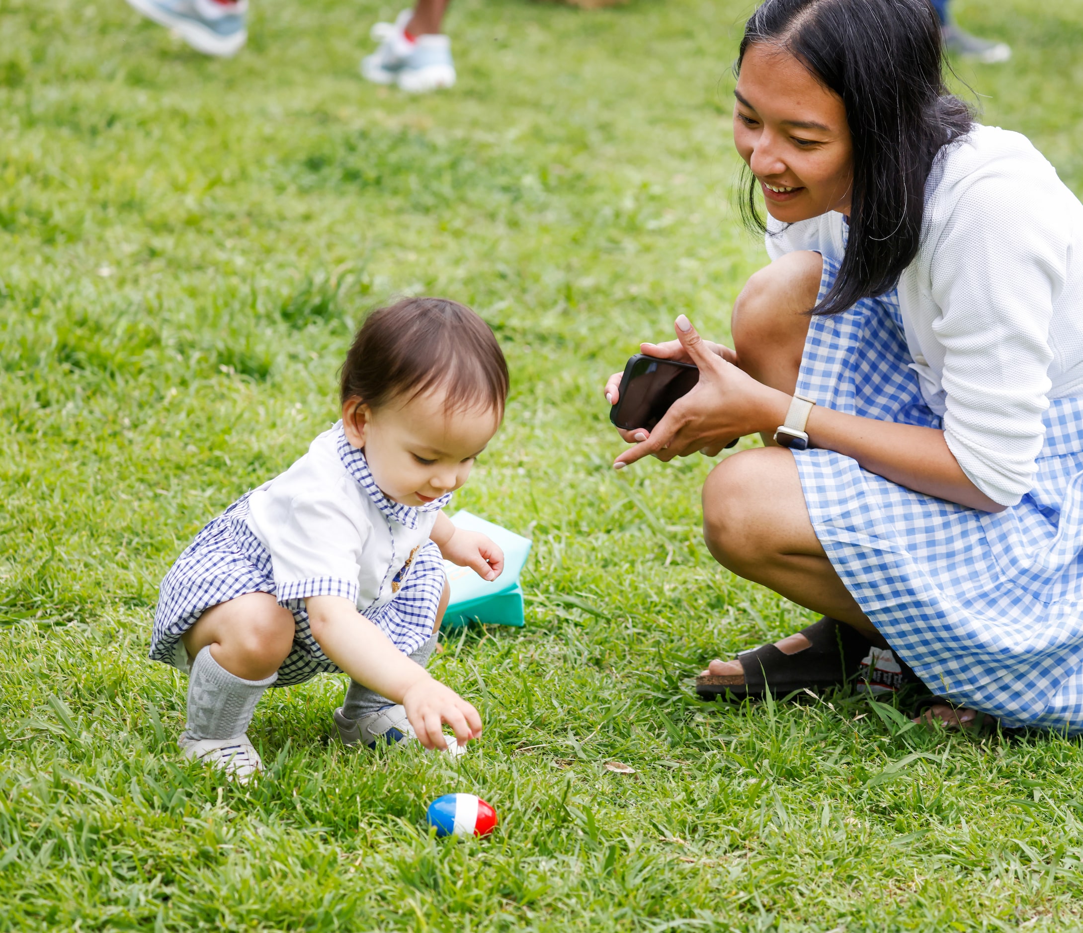 Cameron Baudendistel, 15 months, moves to gather a candy-filled egg placed in the grass by...