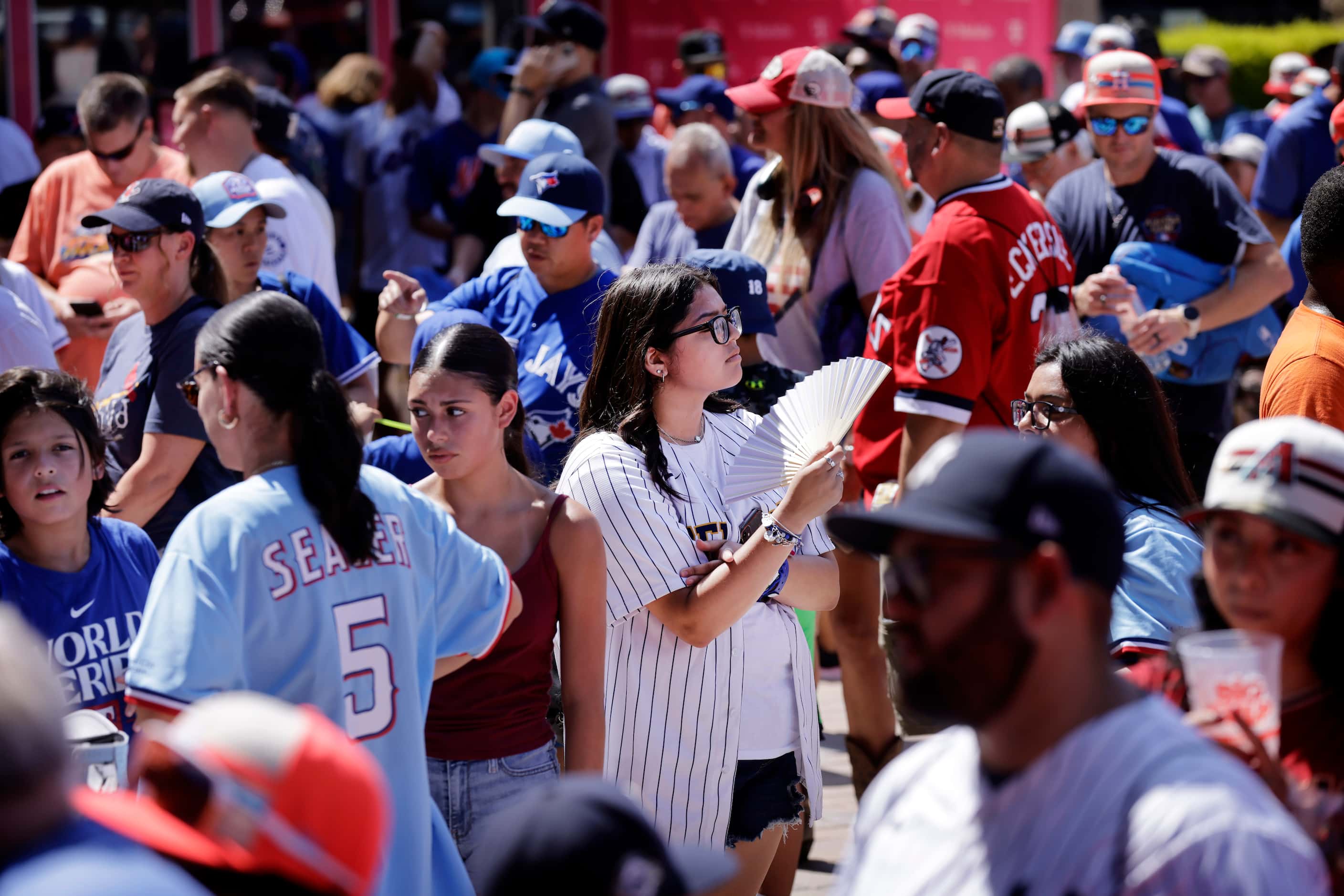 Baseball fan Abigail de la Fuente keeps cool in the hot sun as they wait for the doors to...