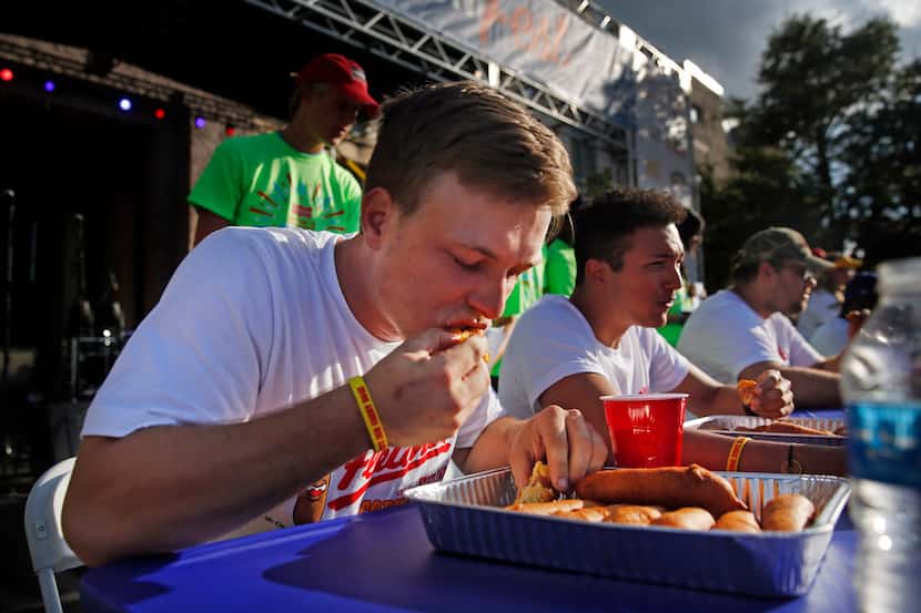 Ty Johnson of Grand Prairie, Texas (left) finished 4 corn dogs in 3 minutes during the...