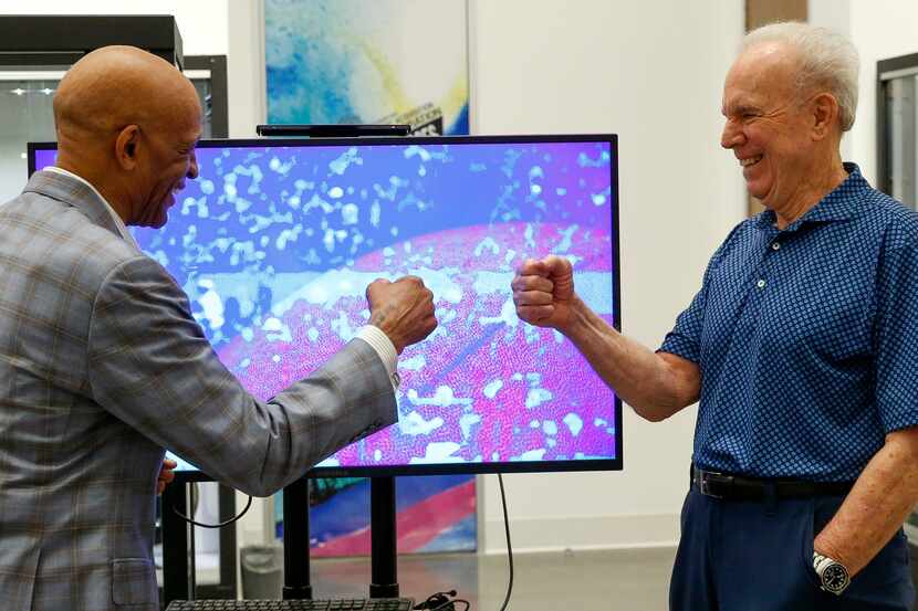 Former Dallas Cowboys players Drew Pearson (left) and Roger Staubach fist bump beside a...