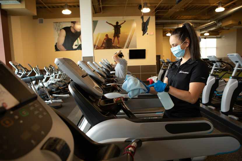 An employee sanitizes treadmills at a 24 Hour Fitness location. The company recently...