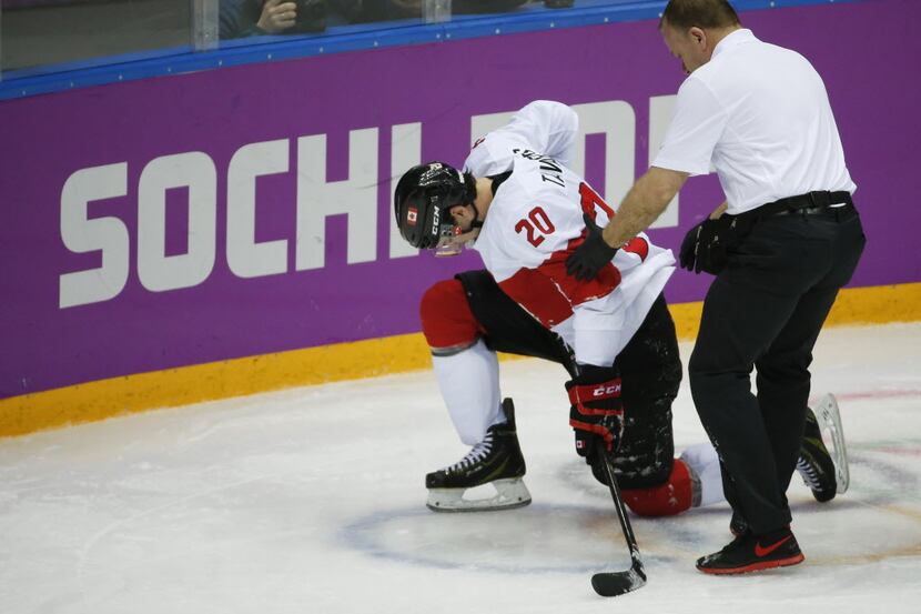 Canada forward John Tavares is helped up off the ice by a trainer during the second period...