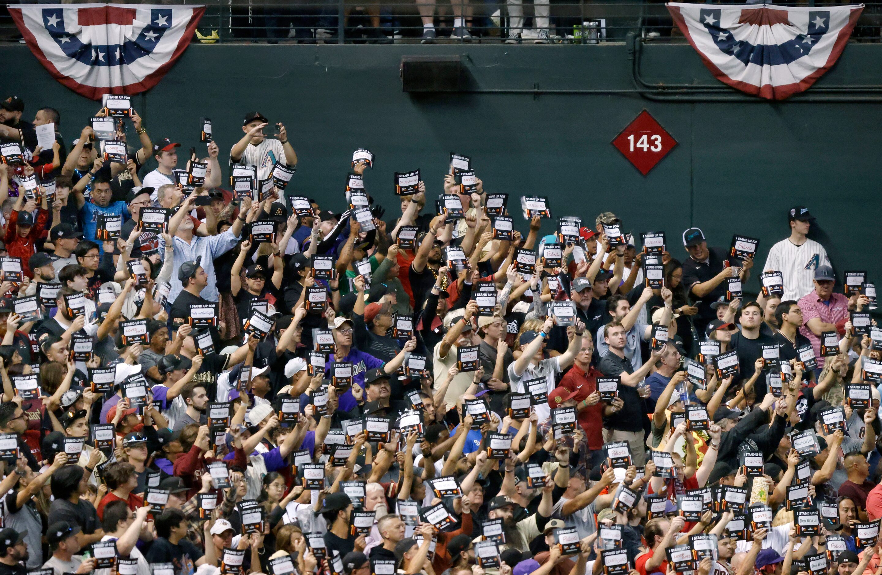 Fans hold up Stand Up to Cancer signs after the fifth inning in Game 4 of the World Series...