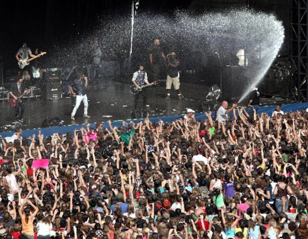 Concert workers spray hundreds of gallons of water into the screaming young crowd as the...