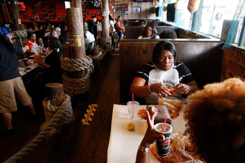 Anissa Collins-Fortune (top) eats shrimp in a booth with her friend Tamieka Stringer at The...