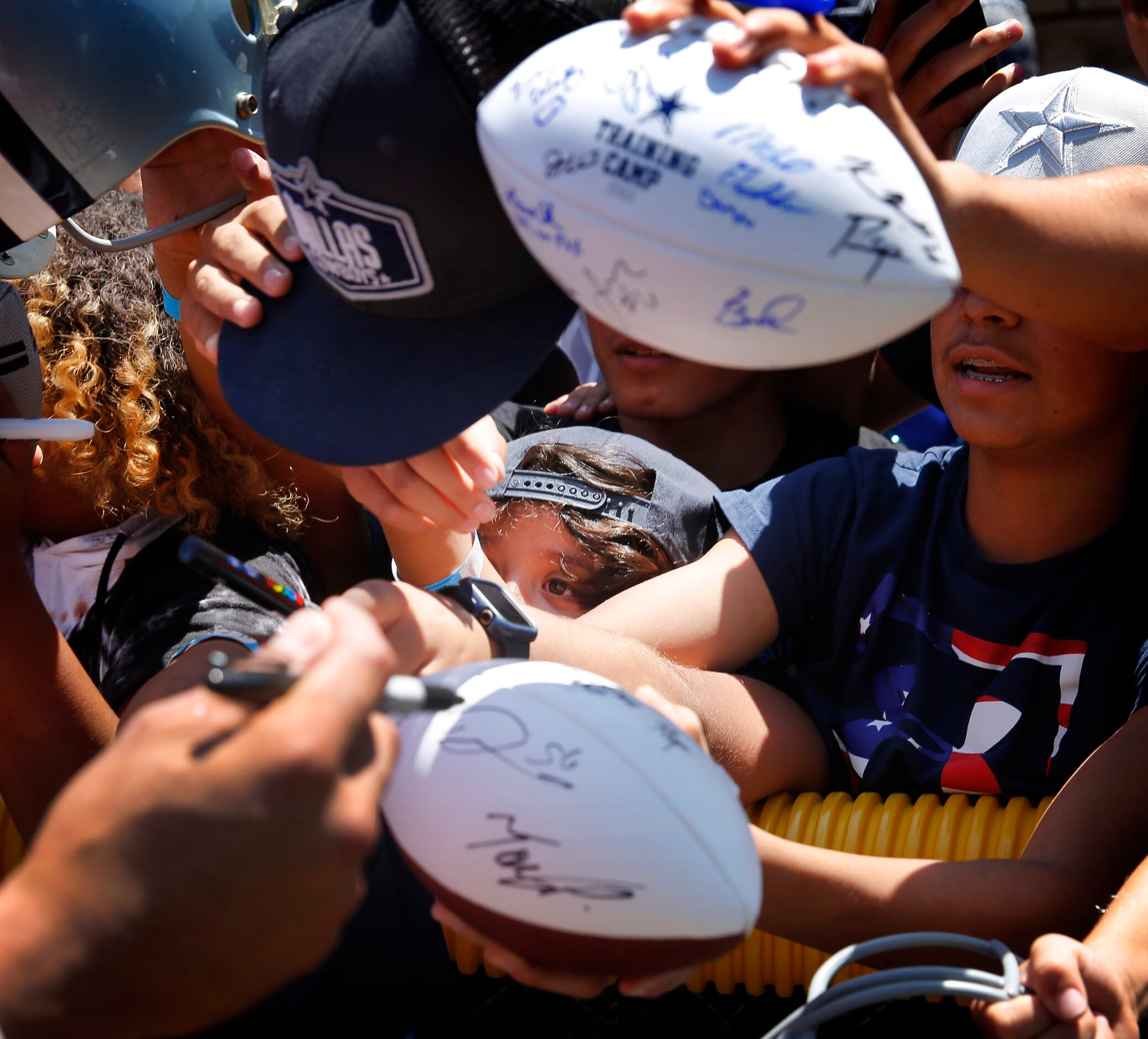 Young fans squeeze through the crowd in hopes of getting an autograph from Dallas Cowboys...