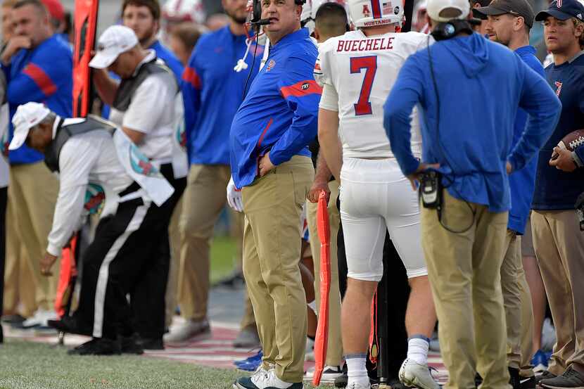 SMU coach Sonny Dykes, center, looks up at the scoreboard during the first half of the Boca...