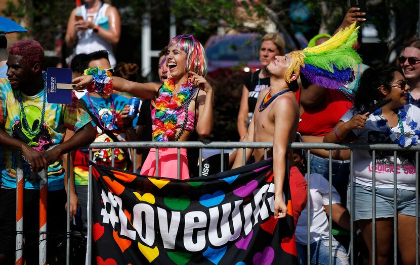 Karla Camacho (center, left) and Adony Rios of Dallas react to people parading by in the...