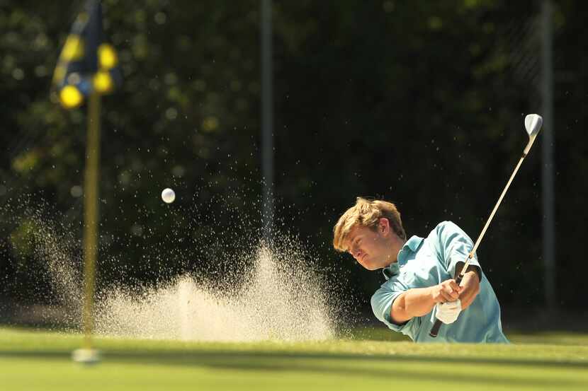 Highland Park High School golfer Jake Potter hits out of a sand bunker during practice at...