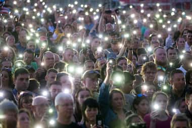 Cellphone flashlights stood in for candles due to high winds at a vigil Sunday in honor of...