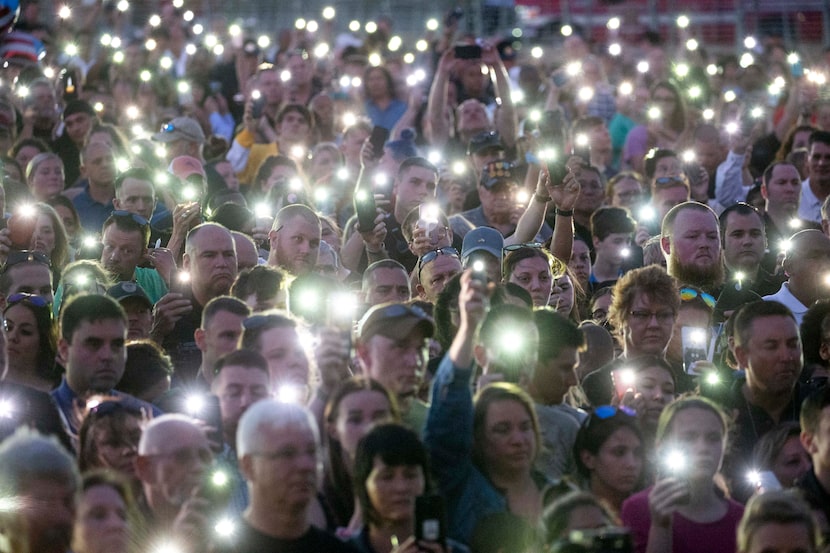 Cellphone flashlights stood in for candles due to high winds at a vigil Sunday in honor of...