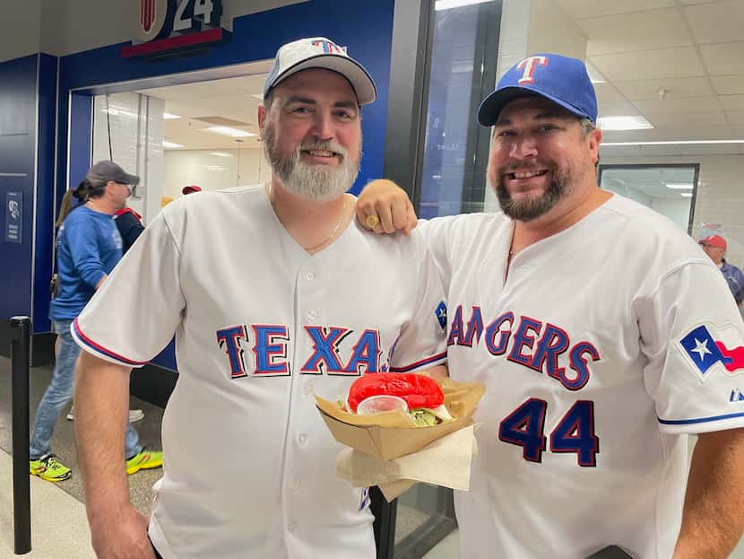 Jeff Henderson y Brian Miller sostienen una Big Tex Torta en el  Globe Life Field, el...