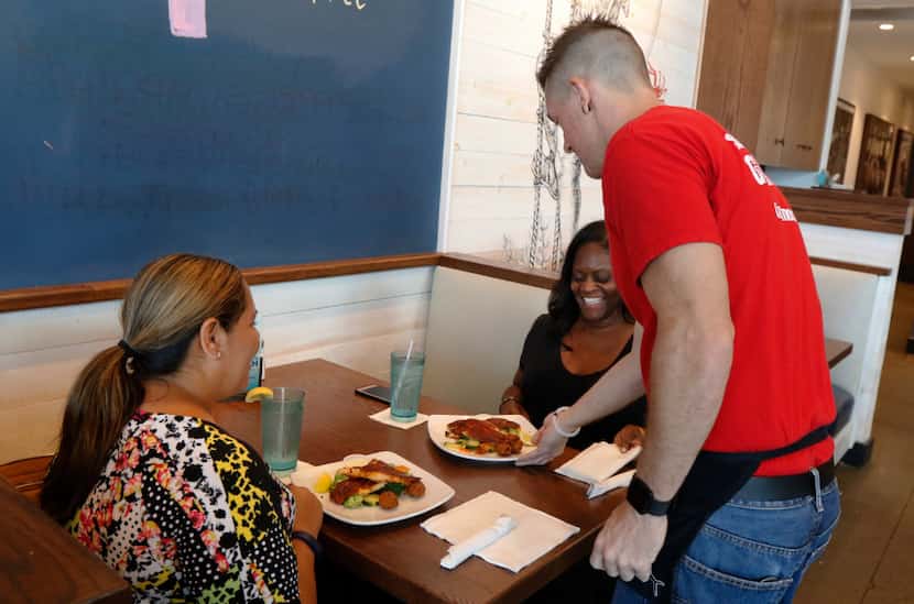 Corey Ahrens, 37, serves lunch to Regina Coter (left) and LaShamda Cole at Fish City Grill...