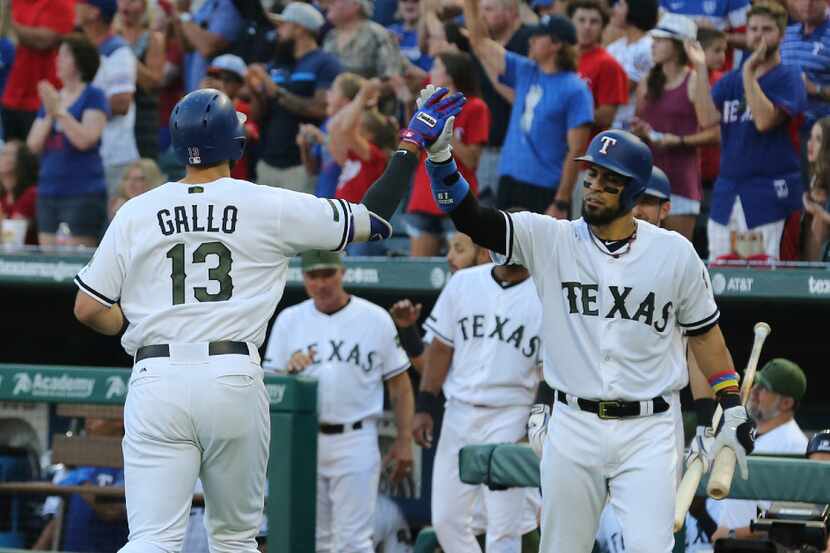 Texas Rangers' Joey Gallo (13) high-fives Robinson Chirinos after a solo home run against...