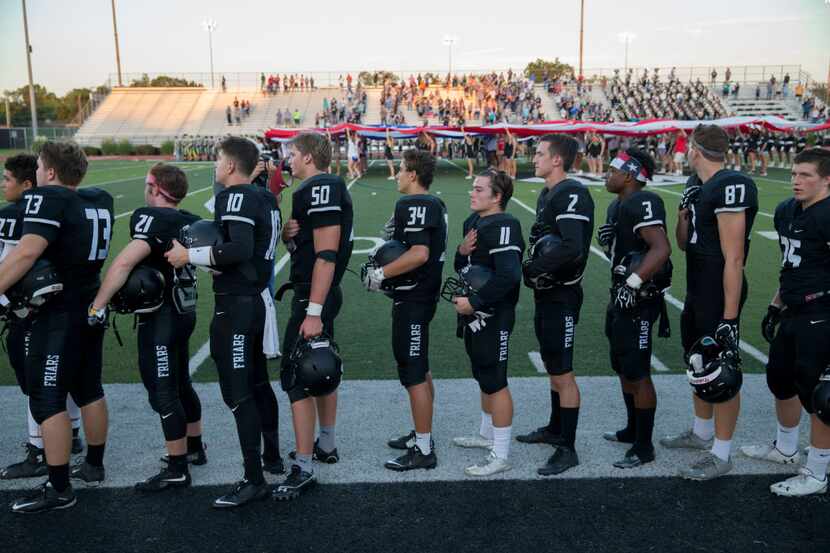 Bishop Lynch Friars players hold their hands-on their hearts during the National Anthem...