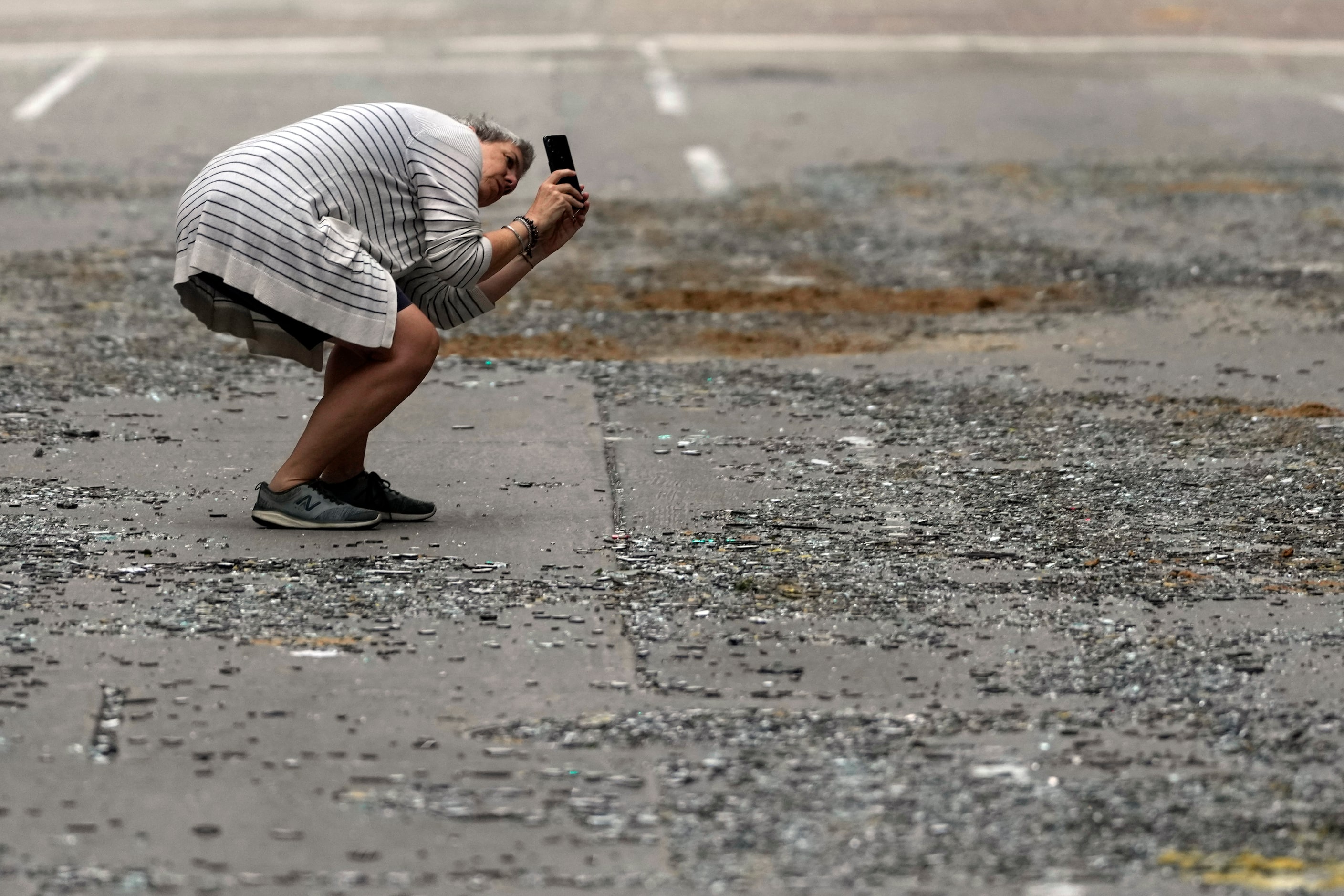 Cheryl Herpich takes a photograph of a downtown building with blown out window in the...