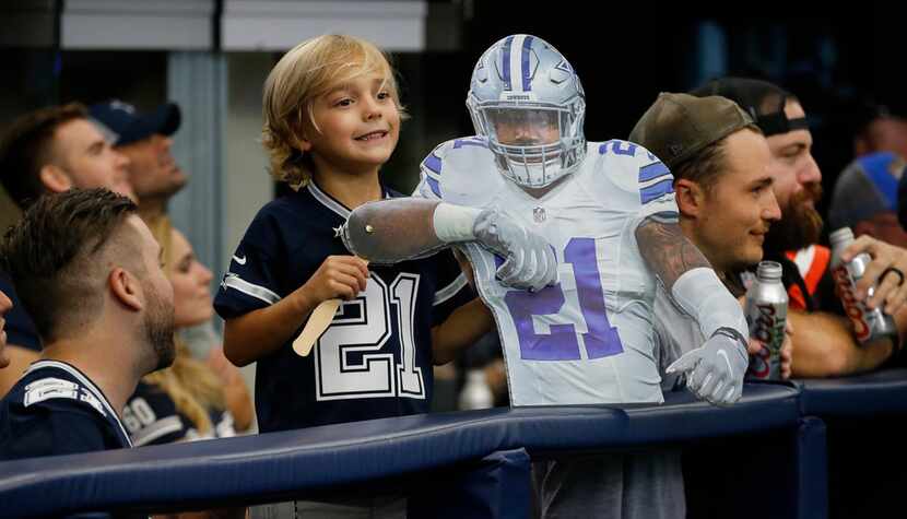 A young fan is all smiles as he holds his cutout of Dallas Cowboys running back Ezekiel...