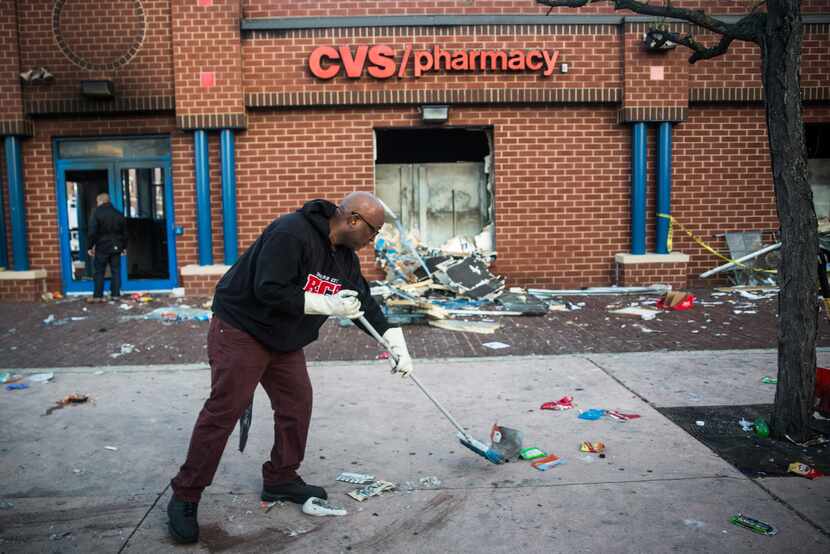 BALTIMORE, MD - APRIL 28:  Jerald Miller helps clean up debris from a CVS pharmacy that was...