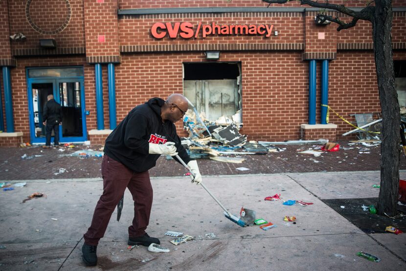 BALTIMORE, MD - APRIL 28:  Jerald Miller helps clean up debris from a CVS pharmacy that was...