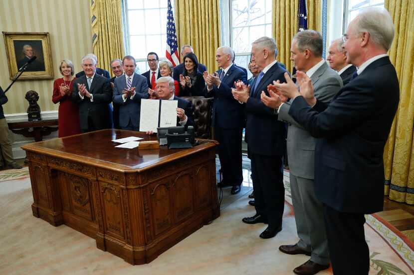 President Donald Trump holds up an executive order after signing it in the Oval Office of...