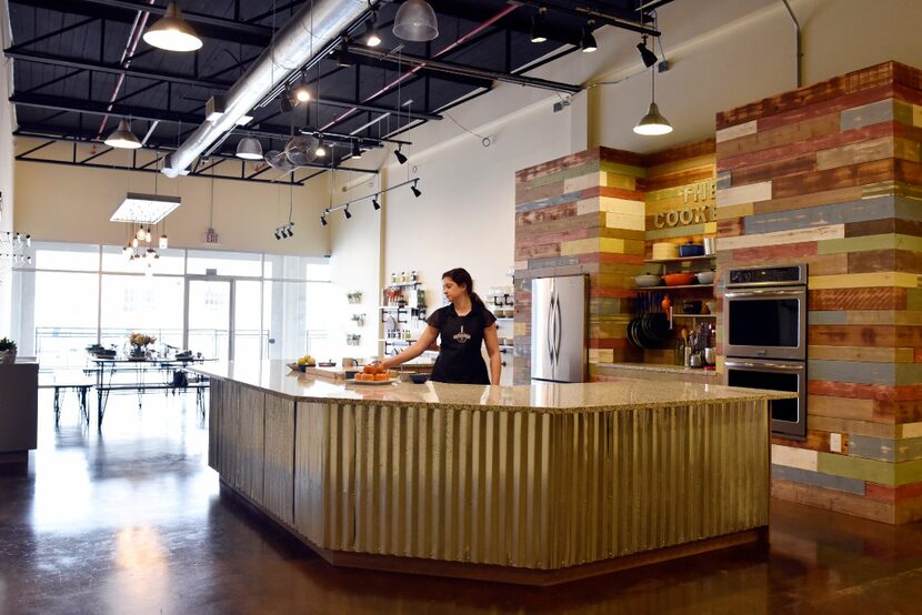 Kelly Huddleston, owner of The Cookery, behind the U-shaped kitchen countertop, where...