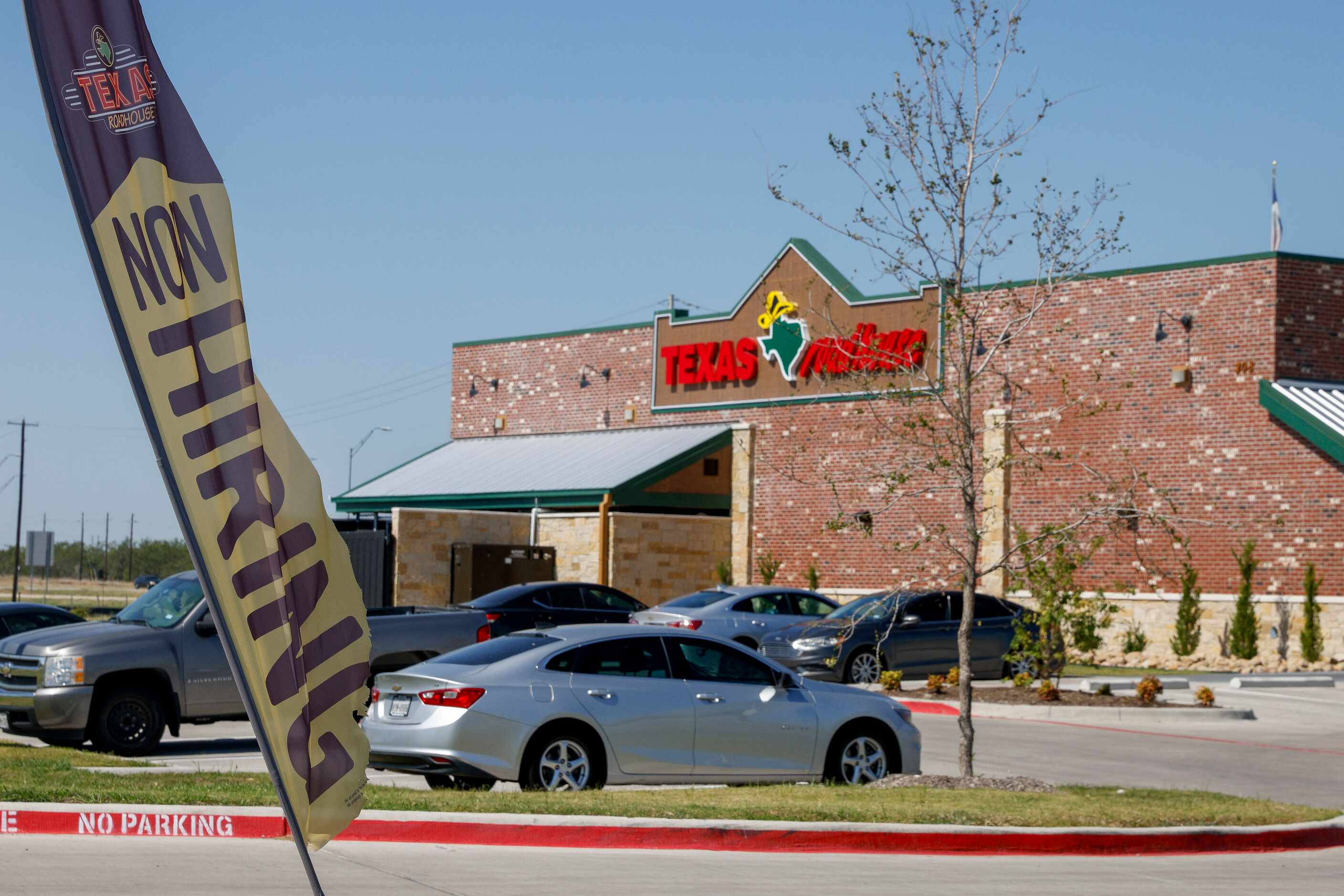 A now hiring sign flies outside the new Texas Roadhouse at the Crossroads at Terrell...