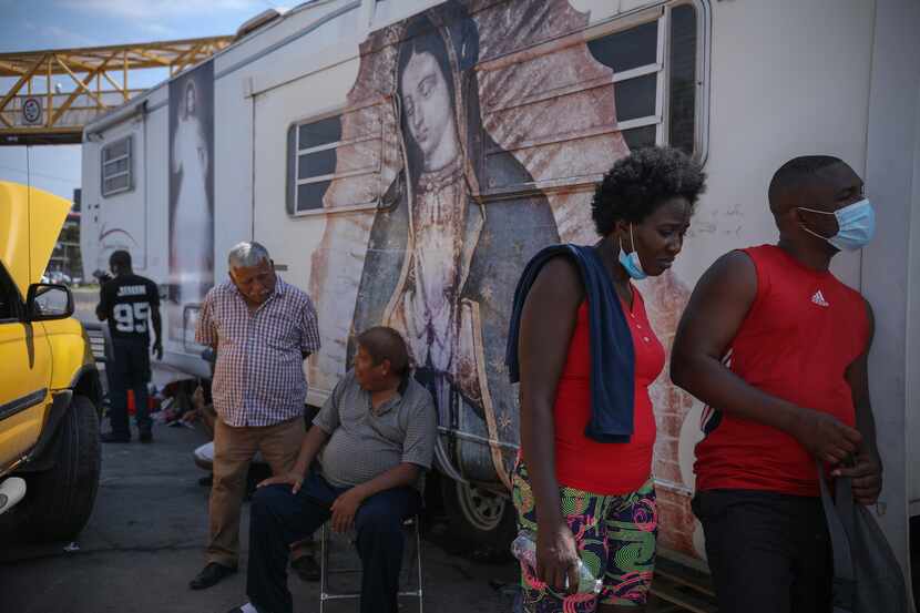 Esther Pierre Louie and John, right,  and his friend stand next to Virgin Mary stamp,...