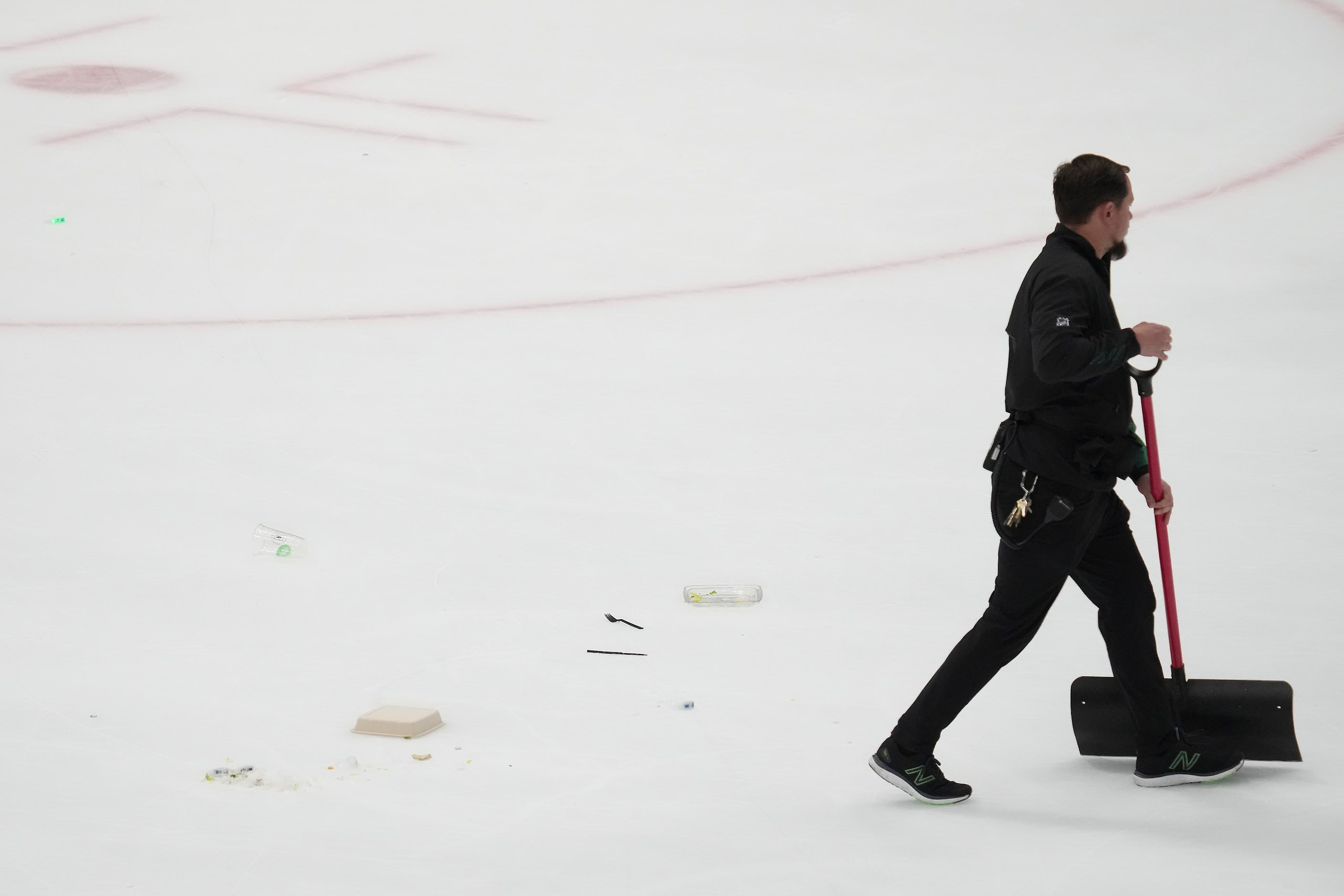 A worker clears trash off the ice that was thrown by fans after Dallas Stars center Max Domi...