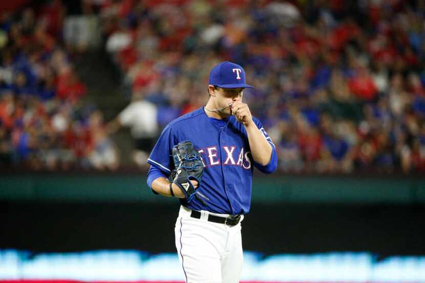 Texas Rangers relief pitcher Derek Holland (45) kisses his necklace before pitching against...