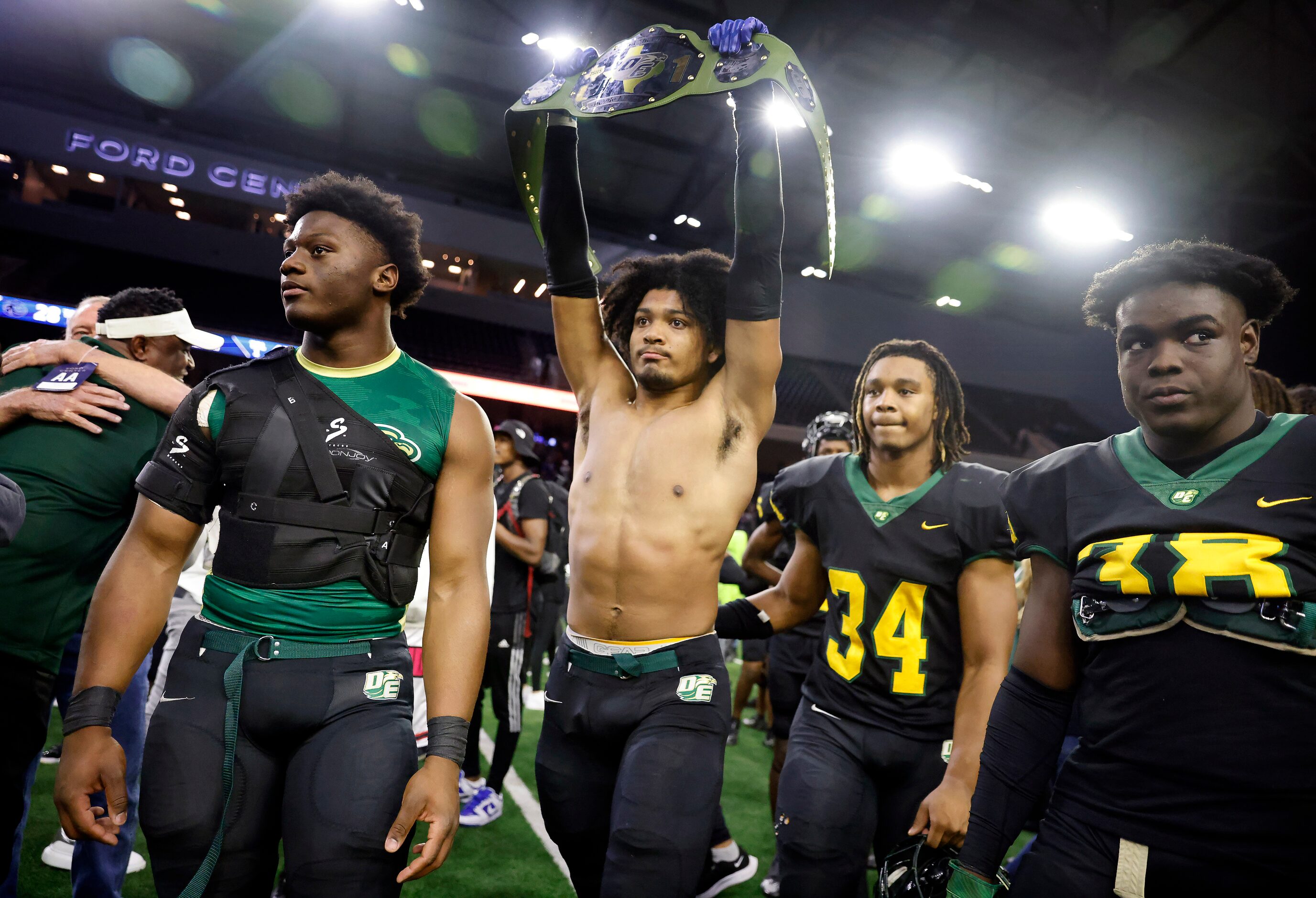 DeSoto outside linebacker Brandon Booker (center) raises up the belt as he and his teammates...