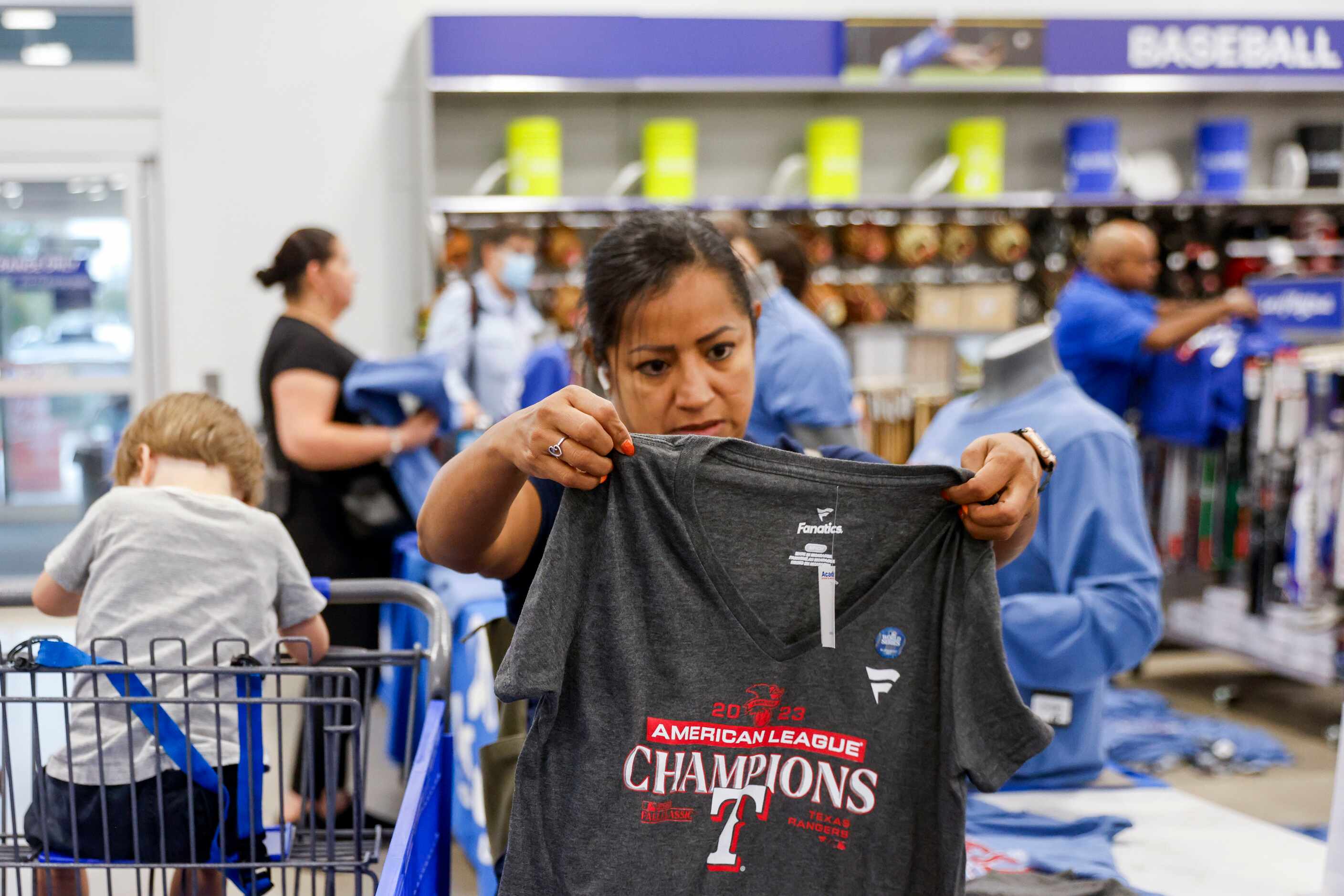 Maria Pecina checks out a Texas Rangers champion theme shirt at Academy Sports + Outdoors,...