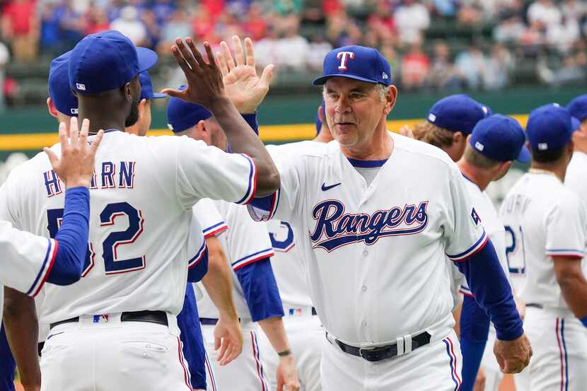 Texas Rangers manager Bruce Bochy high fives relief pitcher Taylor Hearn (52) before the...