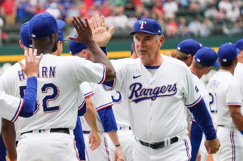 Texas Rangers manager Bruce Bochy high fives relief pitcher Taylor Hearn (52) before the...