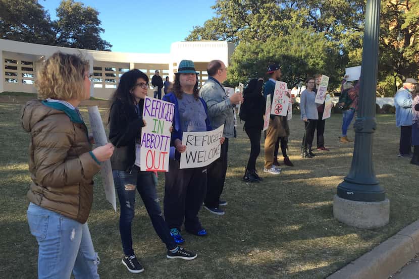  Protesters hold signs supportive of Syrian refugees as motorists pass by Dealey Plaza on...