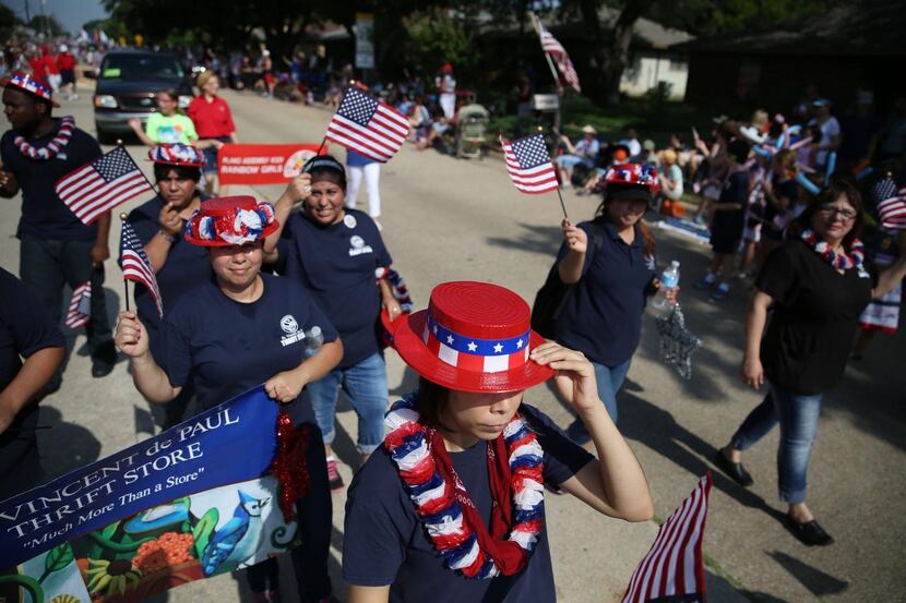 
Denys Ontiveros (center), of Dallas, holds onto her hat while walking with others from the...