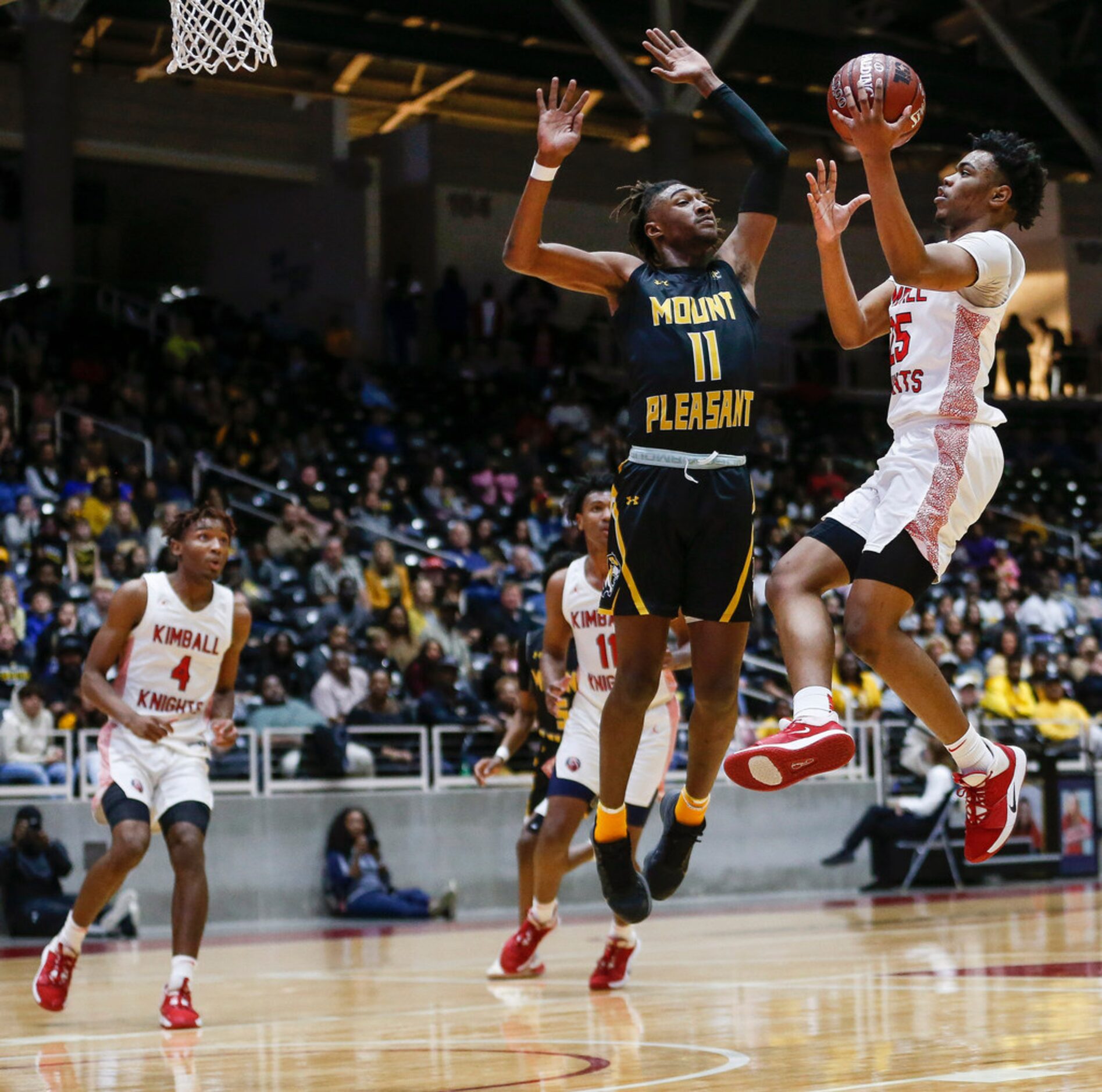 Kimball's Marcus Bonner (25) goes up for a shot against Mount Pleasant's Jamarion Brown (11)...