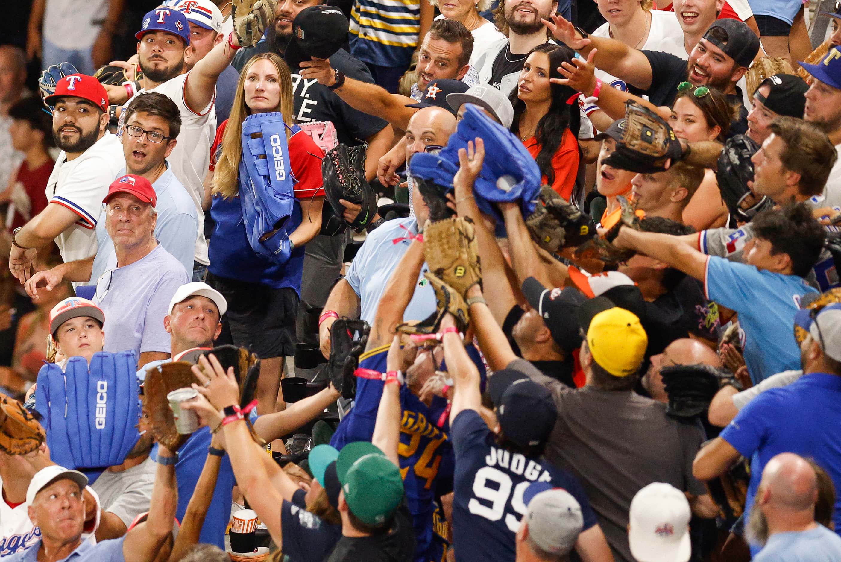 A fan with a large blue glove reaches up to snag a home run ball hit by National League's...