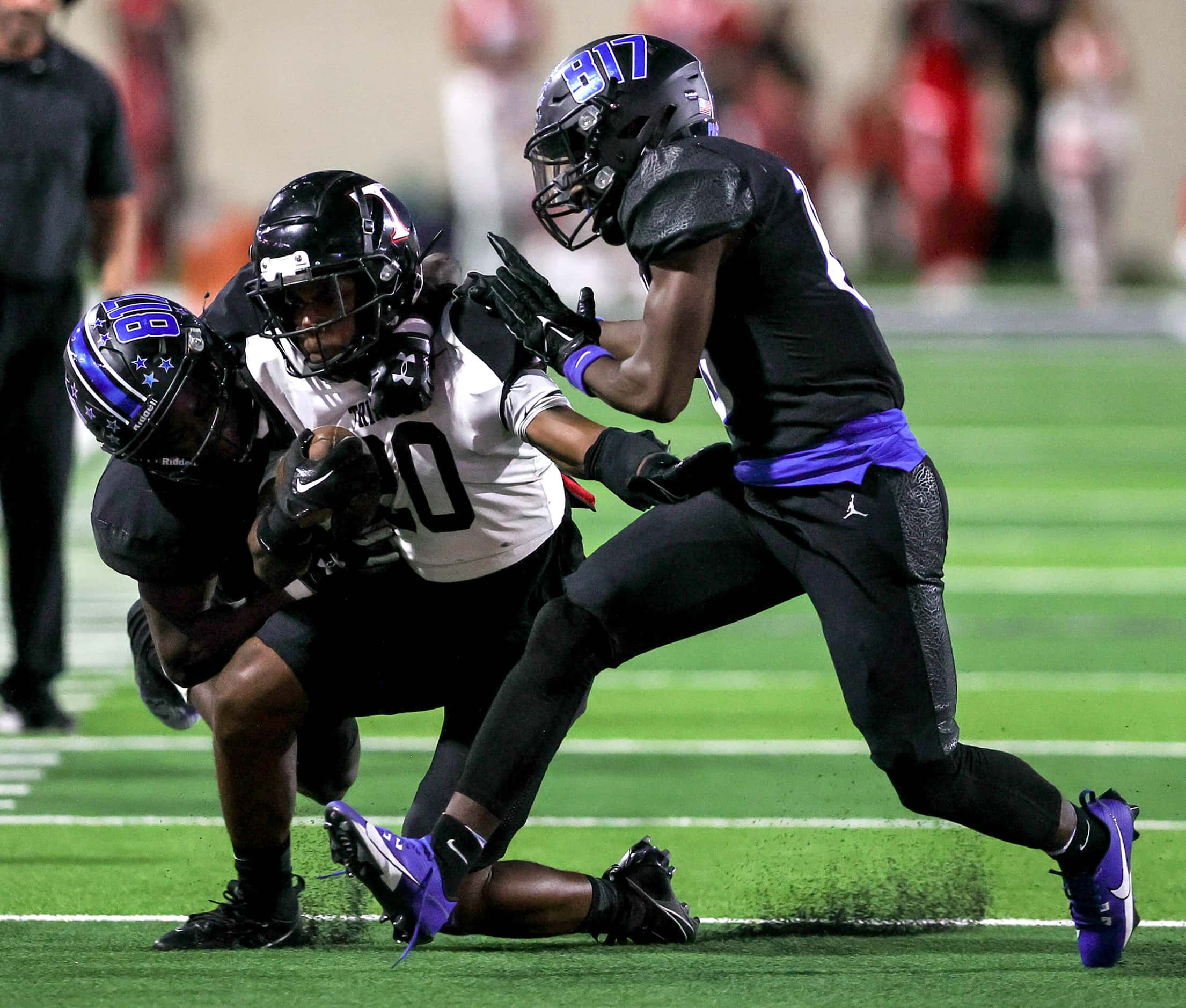 Euless Trinity running back Josh Bell (20) gets dragged down by North Crowley linebacker...