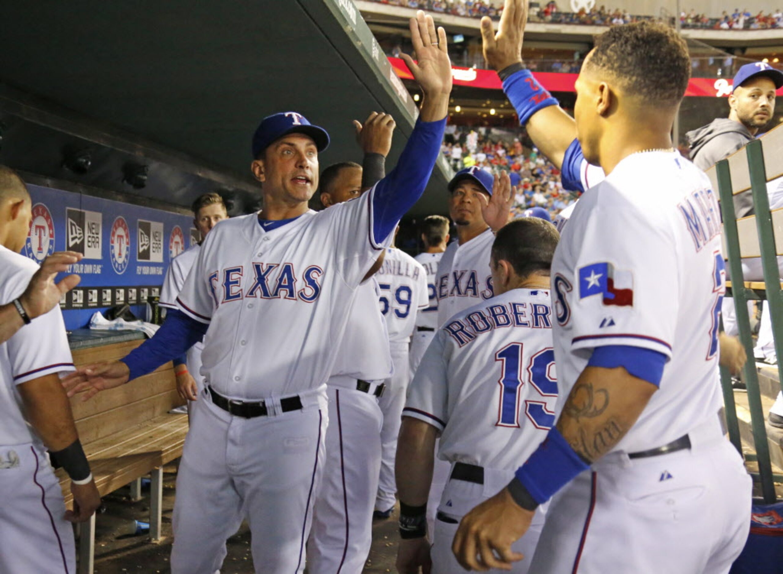 Texas manager Tim Bogar, center, congratulates center fielder Leonys Martin, right, on a...