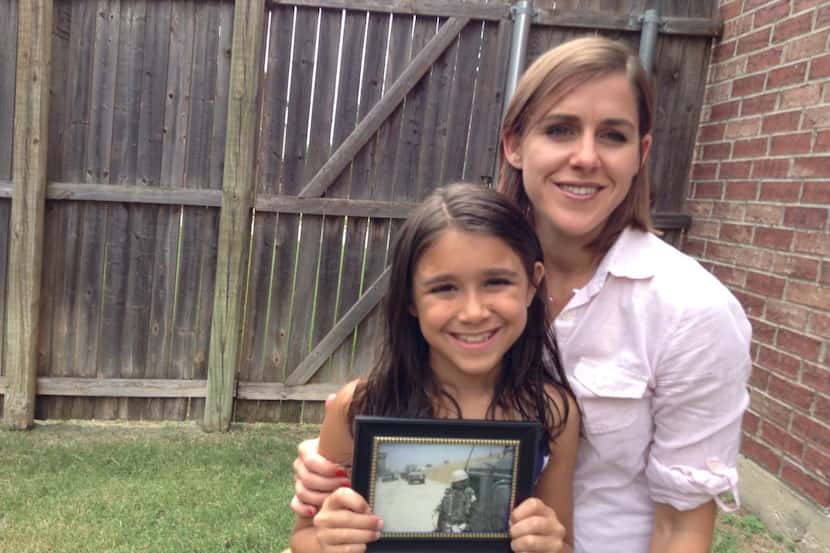 Charity Verre and her daughter, Madi, hold a picture of Michelle Witmer, who died serving in...