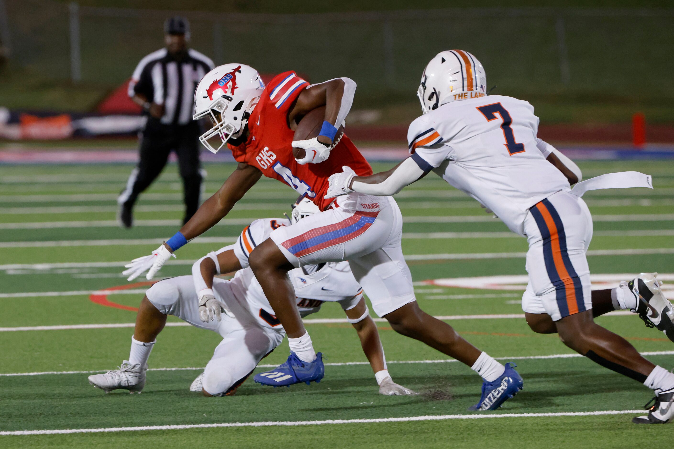 Grapevine’s Demontrez Dunn (7) runs past Frisco Wakeland defenders Aiden Poole and Trent...