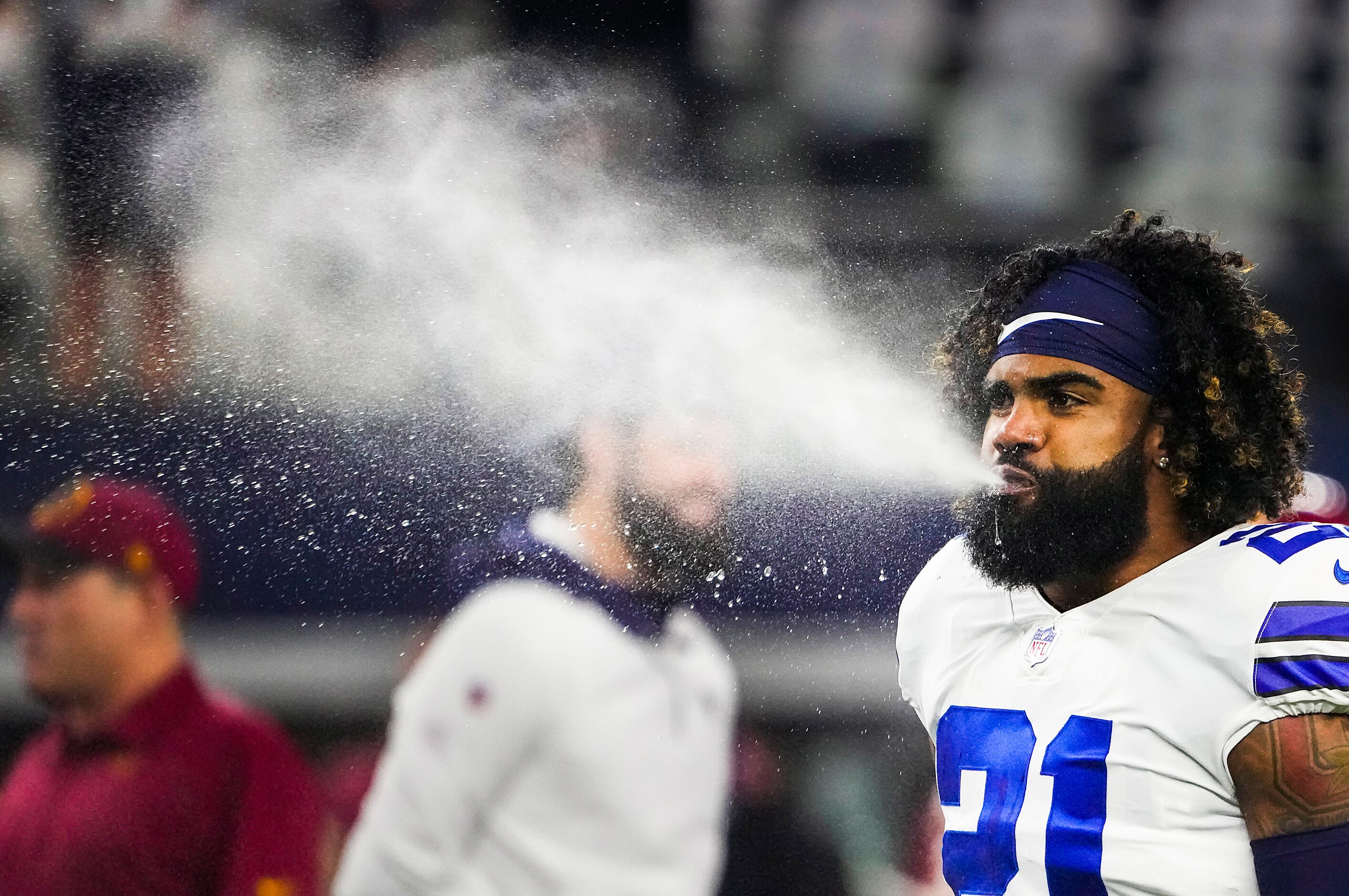 Dallas Cowboys running back Ezekiel Elliott blows water while warming up before an NFL...