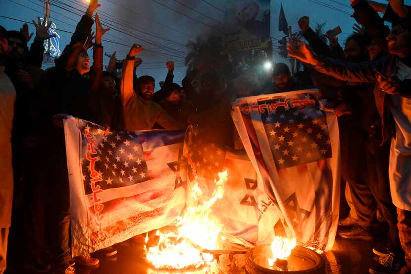 Pakistanis burn U.S. and Israeli flags in a protest against the killing of top Iranian...