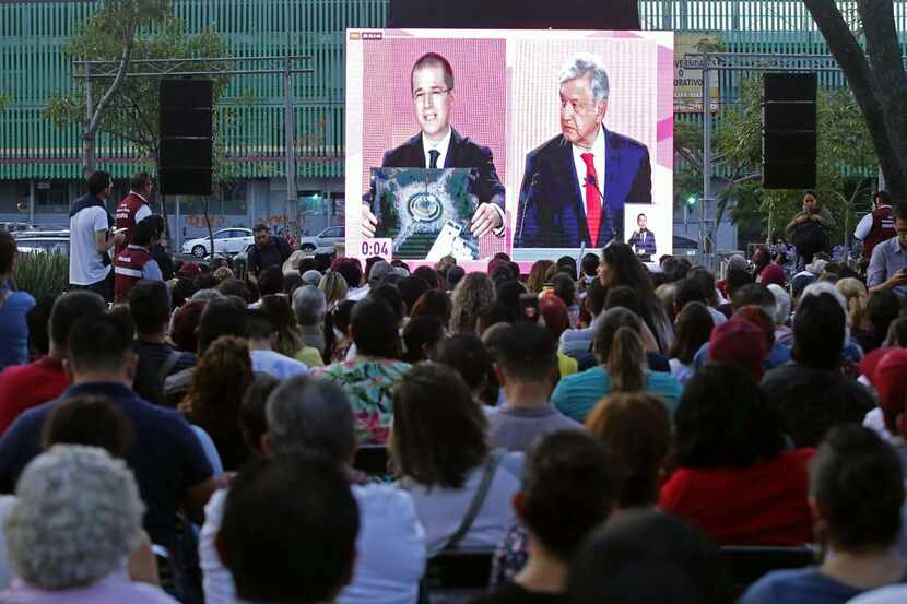 People watch a public television screen showing Mexico's presidential candidate Ricardo...