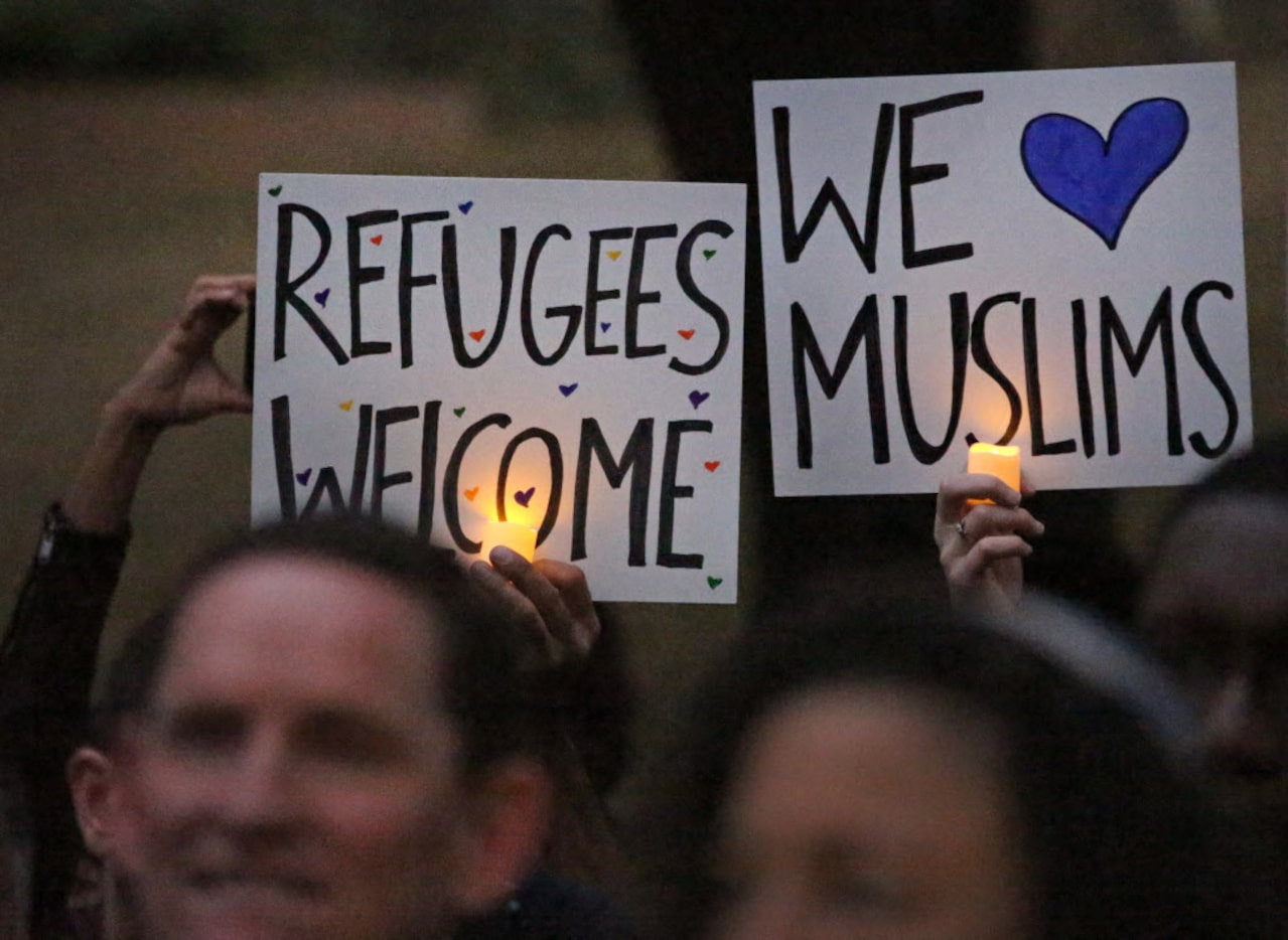 The crowd holds candles during the interfaith vigil to support refugee resettlement in Texas...